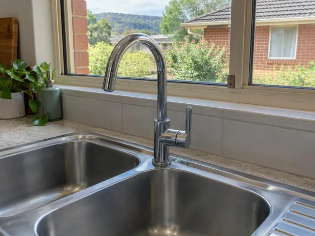 Chrome kitchen mixer tap above a stainless steel sink in a bright home kitchen in Cessnock