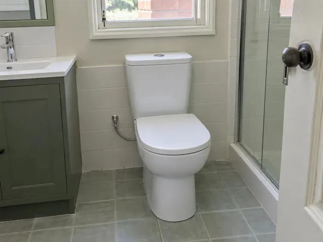 White toilet beside a shower and vanity in a tiled bathroom in Aberdare
